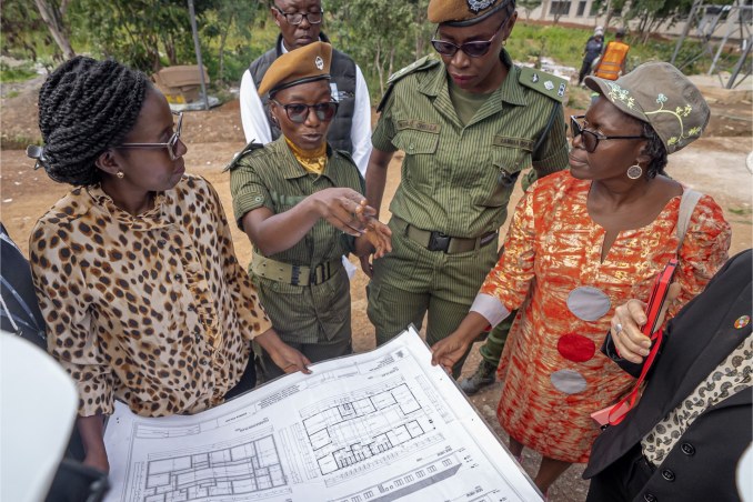 Zambia Police Service personnel and partners review building plans at the site of a new women’s accommodation and childcare facility.